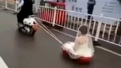 عريس يسحب عروسته خلفه بدراجة نارية في أغرب زفة (فيديو)