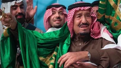 الملك سلمان يتوشح علم المملكة خلال أداء العرضة السعودية