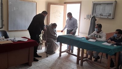 رئيس لجنة يساعد مريضا للتصويت في جولة الإعادة ببني سويف
