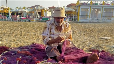 ترقيع الغزل..قصة عم علي العشري يعمل منذ 60 عاما علي شاطئ بورسعيد: مهنة عاوزه الصبر